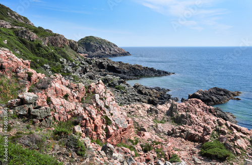 Scenic landscape in the Kullaberg Nature Reserve, Mölle, Skåne, Sweden. Red rocks, summery blue skies and the open Kattegatt sea in the distance.