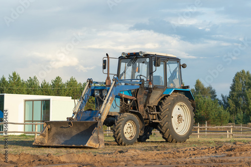 A blue tractor is leveling a construction site for the installation of modular frame houses