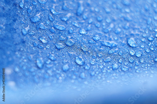 Water drops on the fabric. Rain Water droplets on blue fiber waterproof fabric. Water drops pattern over a waterproof cloth. Blue background.