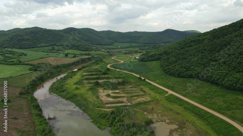 Farmlands and Mountains in Muak Klek, Thailand; an aerial footage towards this awesome valley with a flowing muddy river revealing hills and farmlands and a rural dirt road. photo