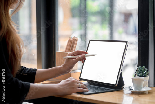 Fényképezés Close-up of a businesswoman hand holding a stylus pen ready to use a tablet blank white screen at the office