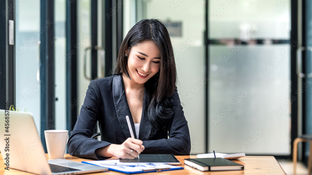 Beautiful Asian businesswoman work using a tablet and a laptop with documents placed at the office. Beautiful Asian businesswoman work using a tablet and a laptop with documents placed at the office.