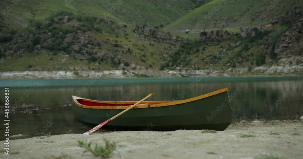 A view to empty boat, standing on the shore of a mountain lake A view to empty boat, standing on the shore of a mountain lake