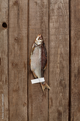 Fototapeta Naklejka Na Ścianę i Meble -  Salted air-dried roach with paper label on wooden background