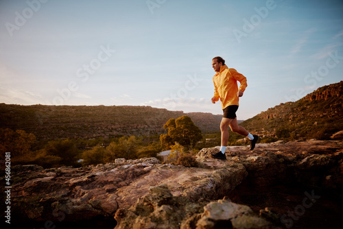 Fitness male running through rocky mountain path