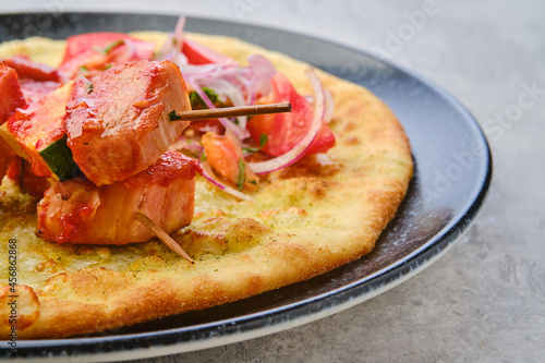 Closeup view of shashlik served on tortilla with tomato and onion