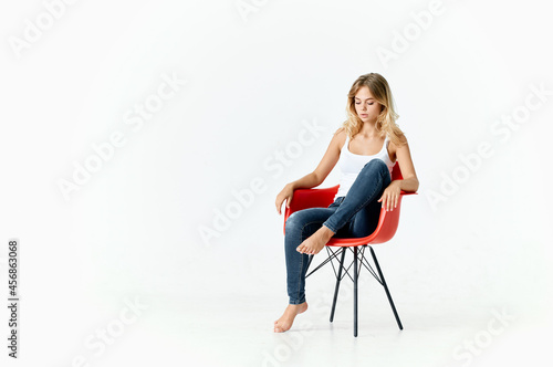 woman on red chair sitting with bent legs fashion elegant style