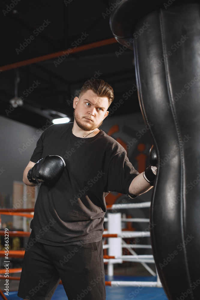 Man in a black t-shirtg boxing in a gym