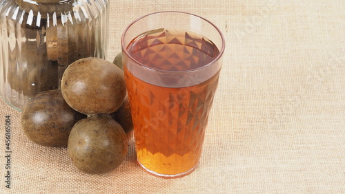 Monk fruit or Luo Han Guo. Dried fruits for healthy sweetener drink. Natural herbal remedy and glass bottle background. Monk fruit drink for who concern health and sugar substitute.  photo