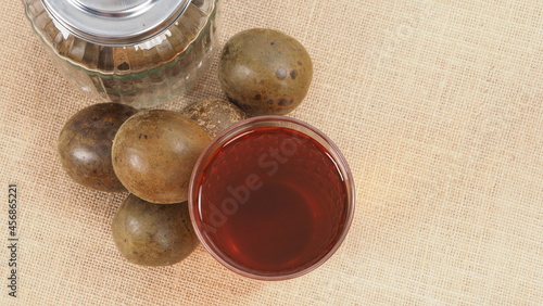 Monk fruit or Luo Han Guo. Dried fruits for healthy sweetener drink. Natural herbal remedy and glass bottle background. Monk fruit drink for who concern health and sugar substitute.  photo