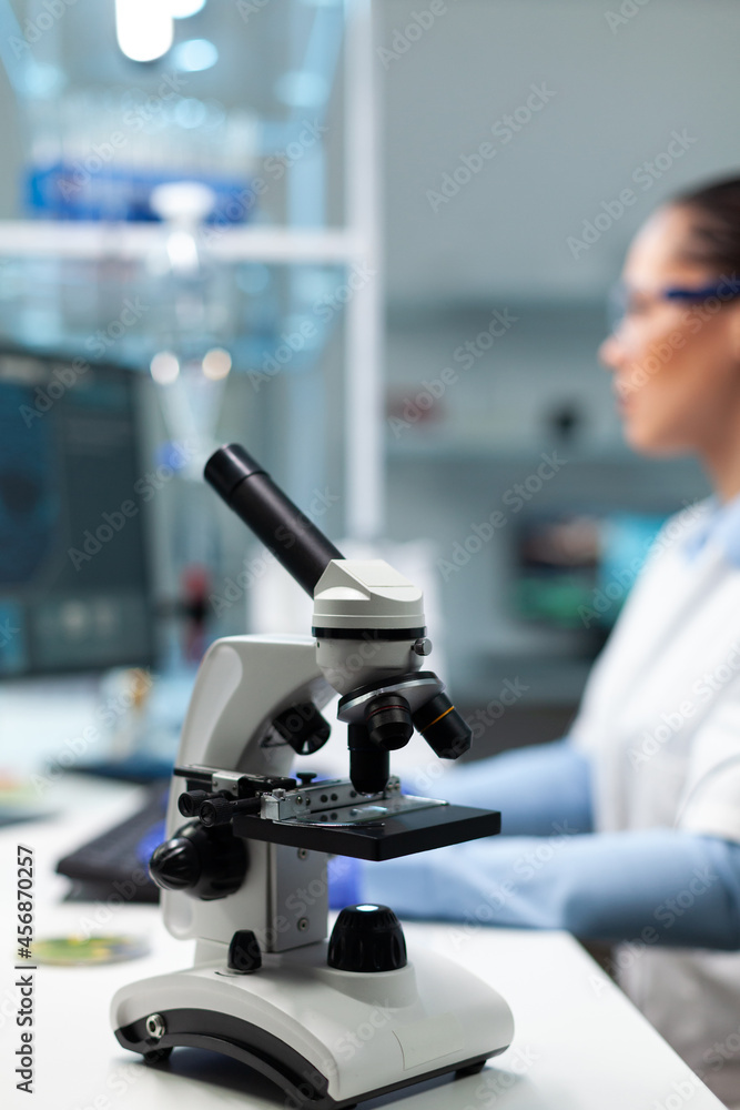 Selectiv focus on medical microscope standing on table in biochemistry hospital laboratory. Specialist microbiologist woman doctor working at biology experiment typing healthcare expertise Selectiv focus on medical microscope standing on table in biochemistry hospital laboratory. Specialist microbiologist woman doctor working at biology experiment typing healthcare expertise
