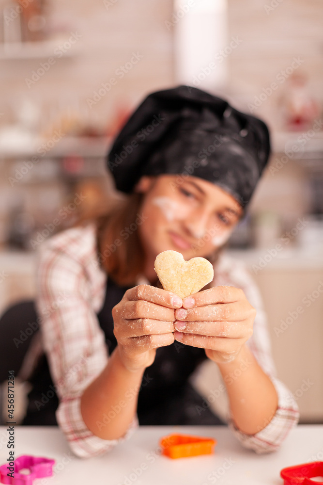 Portrait of smiling kid with apron holding traditional dough cooking gingerbread dessert in xmas culinary decorated kitchen. Grandchild baking homemade dessert at home celebrating christmas holiday Portrait of smiling kid with apron holding traditional dough cooking gingerbread dessert in xmas culinary decorated kitchen. Grandchild baking homemade dessert at home celebrating christmas holiday