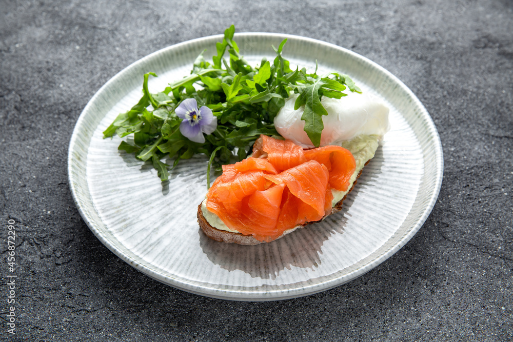 Bruschetta with salmon, poached egg and cheese. Ready menu for the restaurant. Neutral gray blue textured background