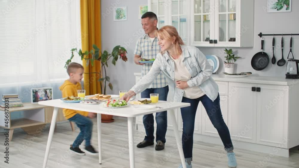 happy married couple together with their son put plates of food on table for dinner together at home background of kitchen happy married couple together with their son put plates of food on table for dinner together at home background of kitchen