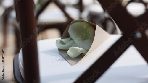 brown wooden chairs with crossed backs close-up. White pillows on chairs and envelopes with white rose petals. against the background of nature on the stone floor. the concept of the holiday.