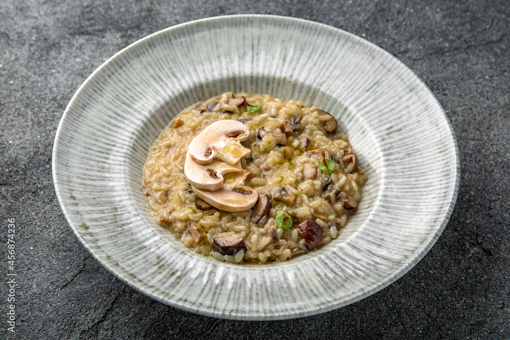 Risotto with wild mushrooms and champignons. Ready menu for the restaurant. Neutral gray blue textured background
