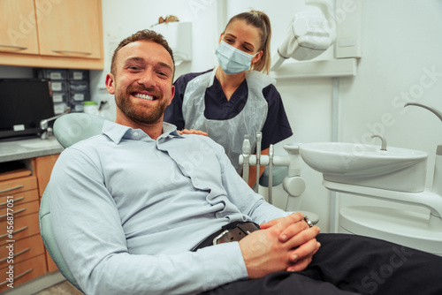 Caucasian male client sitting in dentist chair smiling while visiting orthodontist