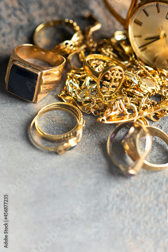 Old and broken jewelry , rings, chain, braclets, watch,  earrings on concrete background for Sell cash for gold concept.Copy space photo