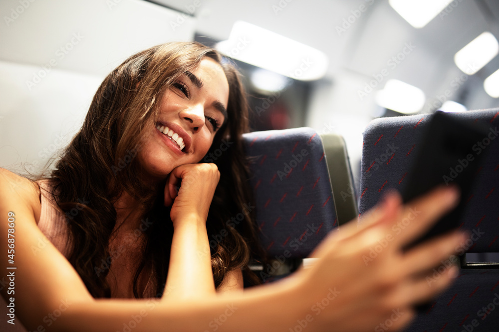Young woman travelling by train. Beautiful girl using the phone while travel