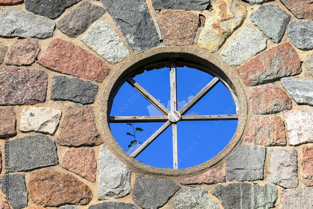 Round window with broken glass in a stone wall