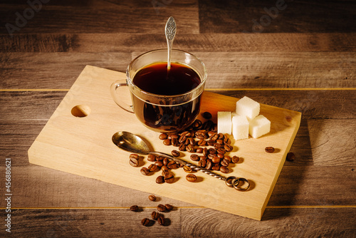 Billede på lærred A cup of black coffee with lumps of sugar and coffee beans on the table