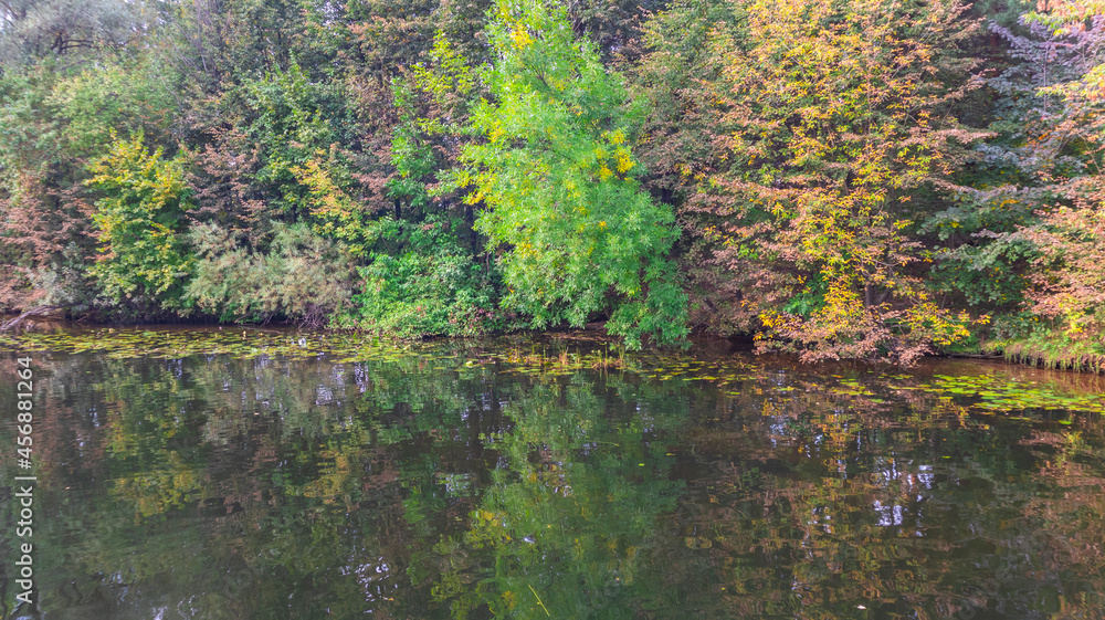Reflection of the autumn forest in the water of a deep lake.
