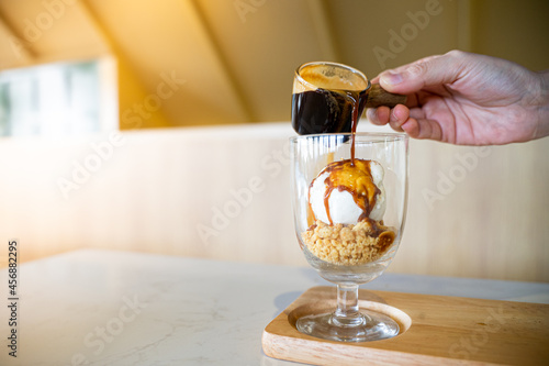 Pouring coffee on vanilla ice cream in a glass to make affogato coffee