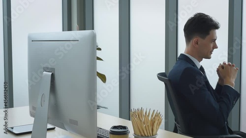 Handsome business man in suit outfit working in front of computer acting success and happy in modern office