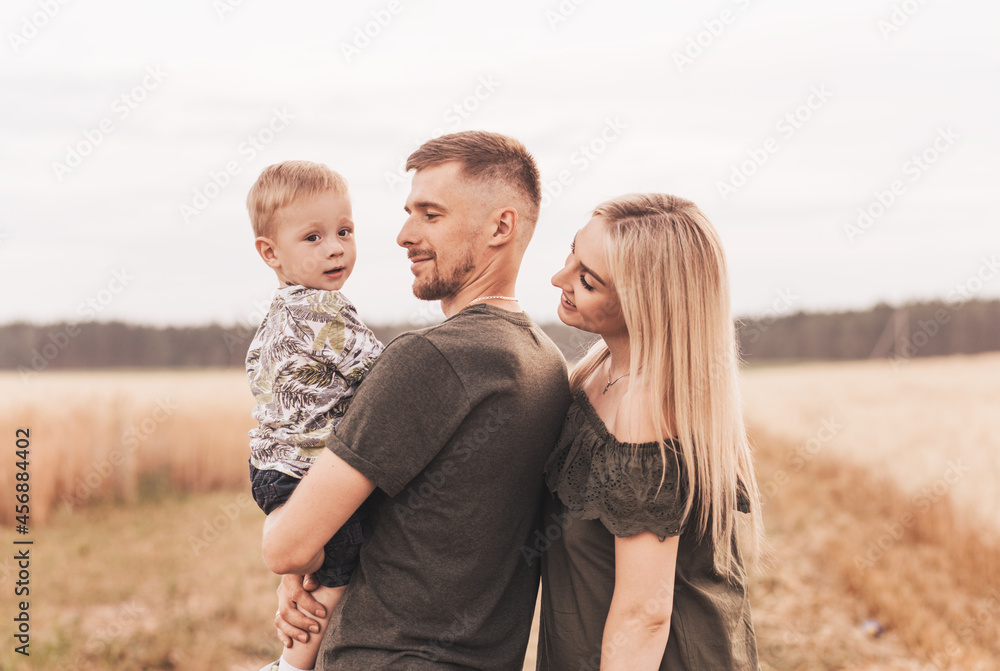 Beautiful family parents and a young son in a wheat field. Mom, Dad and Baby Together. Happy family, parents hugs their little son Beautiful family parents and a young son in a wheat field. Mom, Dad and Baby Together. Happy family, parents hugs their little son