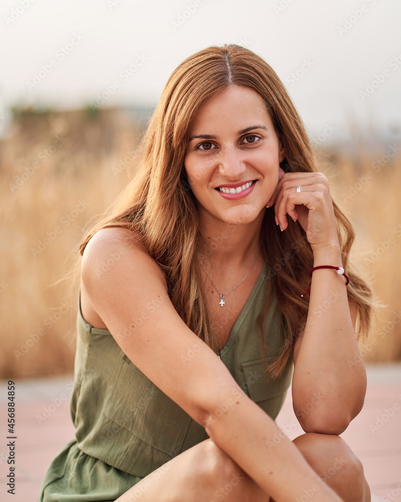 Portrait of a pretty young woman sitting on the sidewalk on the street with a nice out of focus background. Portrait of a pretty young woman sitting on the sidewalk on the street with a nice out of focus background.