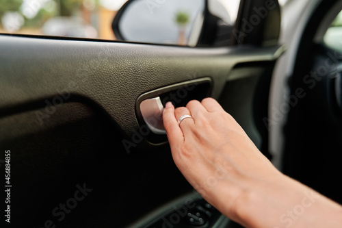 Detail view of a woman's hand opening a car door from the inside.