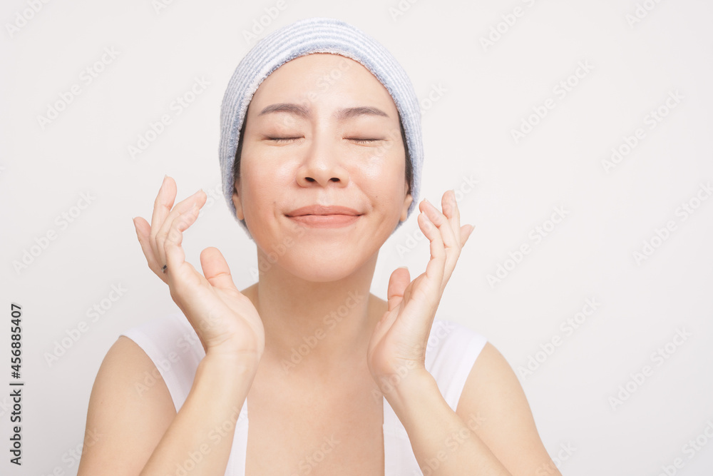 Portrait of a beautiful asian woman with no makeup smiling eyes closed feeling happy for her smooth, soft and clean facial skin after her routine facial skincare. K beauty, Glowing, Cleansing. Portrait of a beautiful asian woman with no makeup smiling eyes closed feeling happy for her smooth, soft and clean facial skin after her routine facial skincare. K beauty, Glowing, Cleansing.