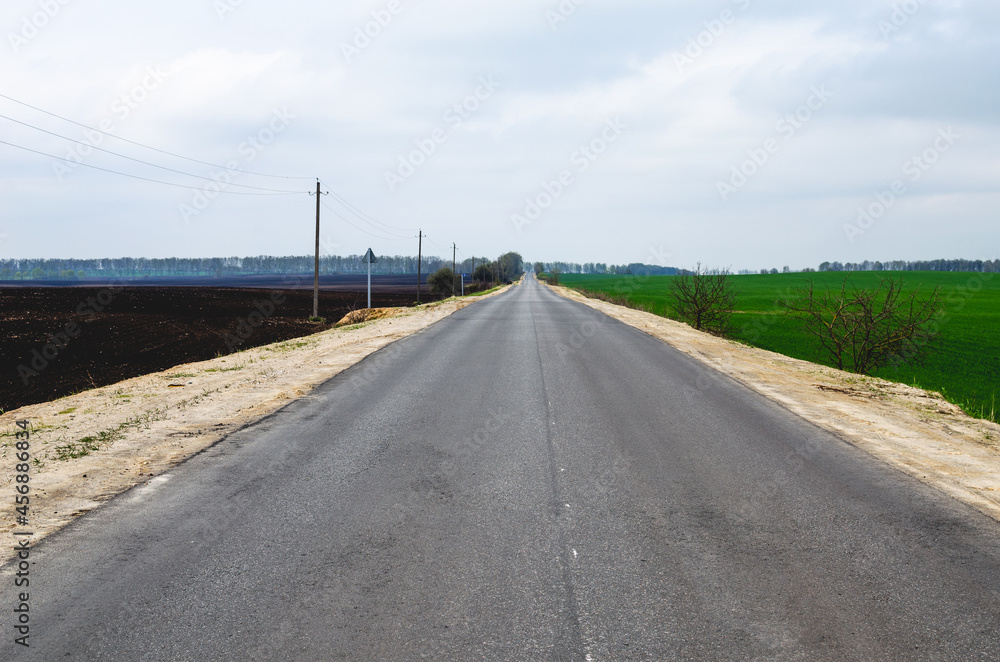 A long road stretching into the distance under a gray blue sky A long road stretching into the distance under a gray blue sky