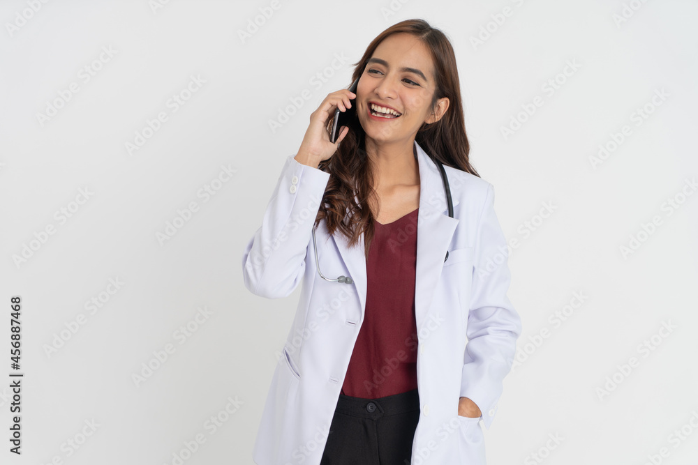 a female doctor in a white uniform smiling while making a phone call a female doctor in a white uniform smiling while making a phone call