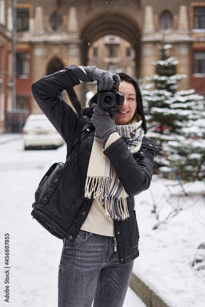 young beautiful woman in winter with a camera on the street takes a picture young beautiful woman in winter with a camera on the street takes a picture