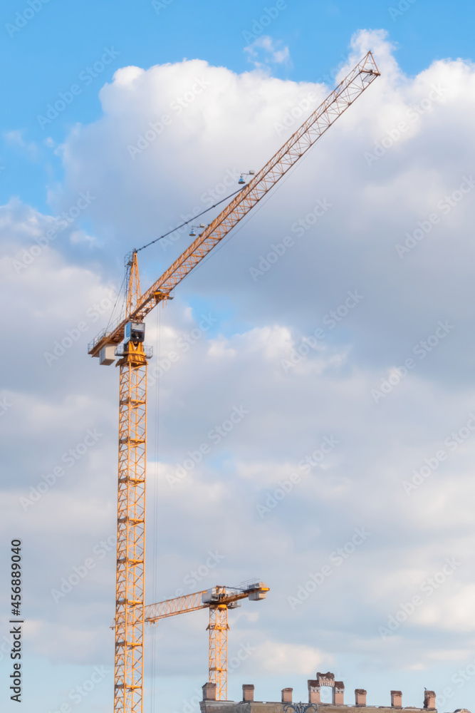 Yellow tower construction cranes against summer cloudy sky. Building process, architecture, urban, engineering, industrial and development concept Yellow tower construction cranes against summer cloudy sky. Building process, architecture, urban, engineering, industrial and development concept