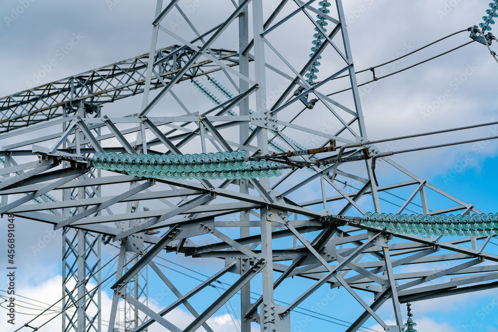 Day view of electric wire station. Dark electric energy technologies. Pylons or transmission towers in countryside on beautiful blue sky background. Cropped view Day view of electric wire station. Dark electric energy technologies. Pylons or transmission towers in countryside on beautiful blue sky background. Cropped view