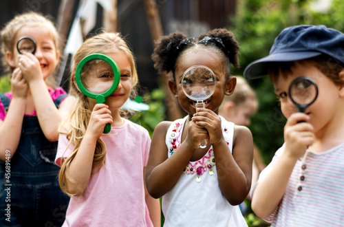 Group of kindergarten kids friends holding magnifying glass for explore photo