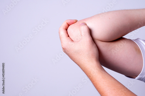 a man massages his elbow to suppress pain