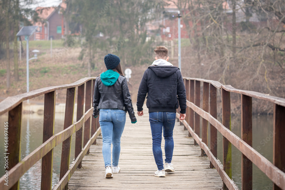Young couple walking on an old wooden bridge on a foggy winter day at Lake Gebart in Zalaegerszeg, Hungary Young couple walking on an old wooden bridge on a foggy winter day at Lake Gebart in Zalaegerszeg, Hungary