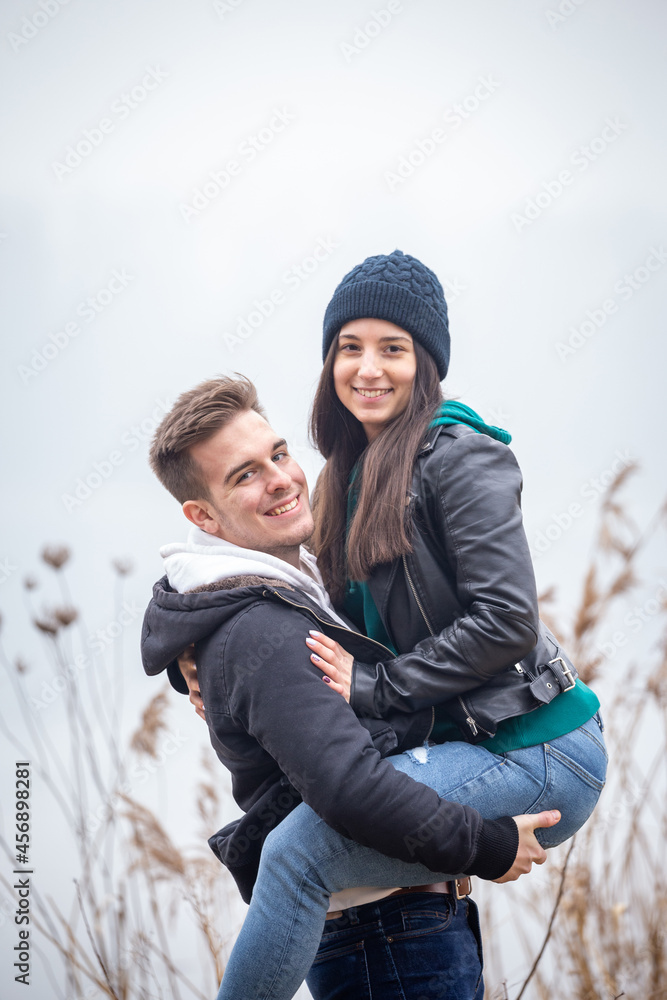 Young couple having fun in nature on a foggy winter day