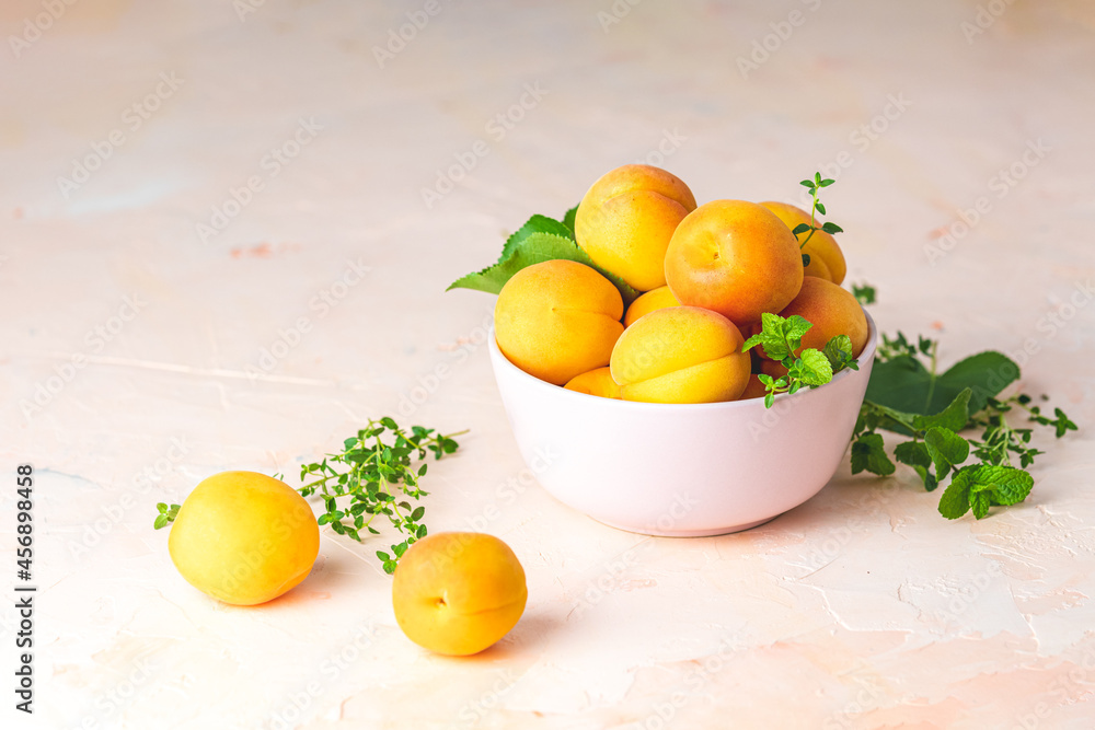 Fresh sweet yellow orange apricots in pink bowl on the pink concrete surface table Fresh sweet yellow orange apricots in pink bowl on the pink concrete surface table