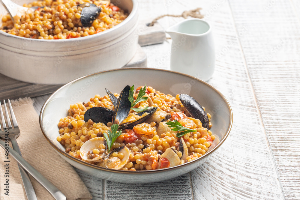 Seafood pasta. Fregula with seafood on a white wood surface. Seafood pasta. Fregula with seafood on a white wood surface.