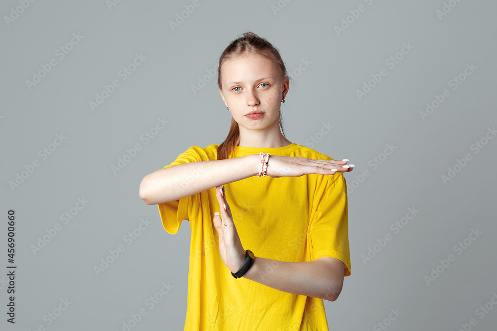 Serious teen girl making time out gesture , isolated on light grey background, wearing in casual blank yellow t shirt. Stop, no, stay back. Time concept Serious teen girl making time out gesture , isolated on light grey background, wearing in casual blank yellow t shirt. Stop, no, stay back. Time concept