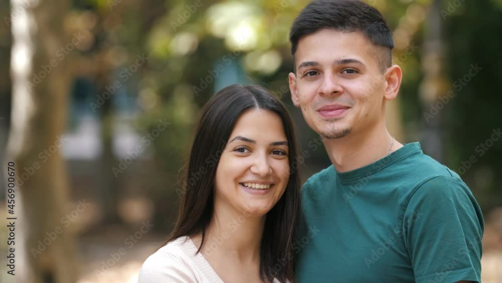 Cheery young family standing, hugging and smiling in green street in summer Cheery young family standing, hugging and smiling in green street in summer