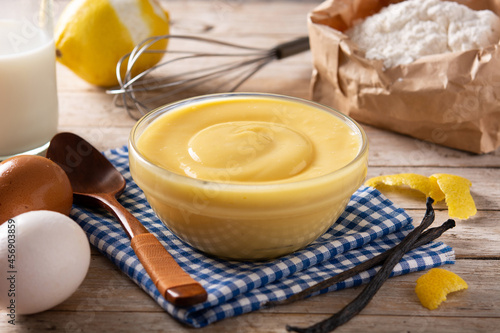Obraz na płótnie Pastry cream in a bowl and ingredients on wooden table