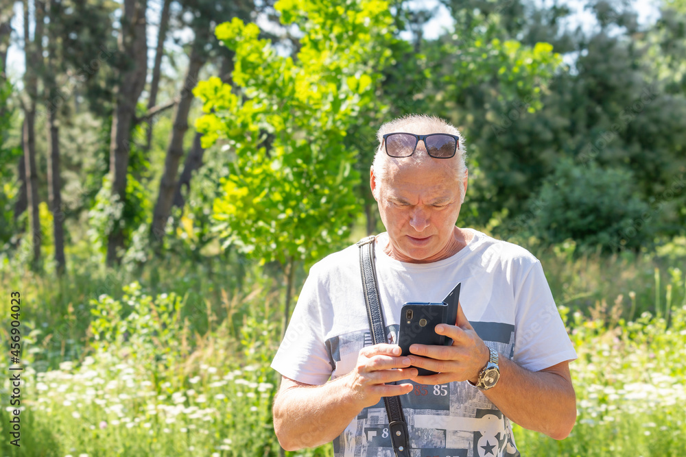 An elderly man using a smartphone in nature An elderly man using a smartphone in nature