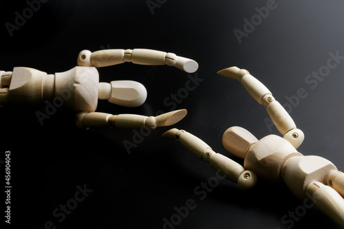 Two wooden mannequins hold out their hands to each other against a dark background. The concept of loneliness, gender identity and finding a partner photo