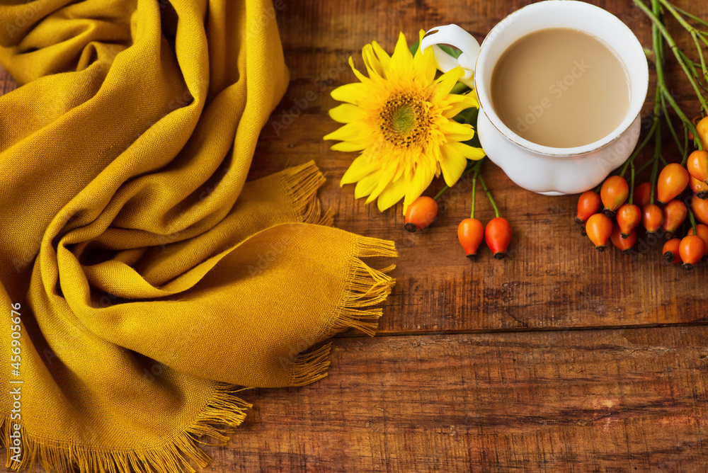 autumn tea cup composition with milk, yellow scarfs, sunflower and rosehip on a wooden background autumn tea cup composition with milk, yellow scarfs, sunflower and rosehip on a wooden background