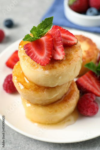 Delicious cottage cheese pancakes with fresh berries, mint and honey on light table, closeup